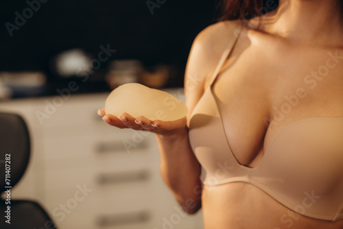 Close up of female body - beauty industry and cosmetic plastic surgery concept. Woman holding silicone breast implant for breast augmentation photo