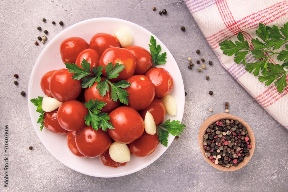 A bowl with pickled tomatoes and spices on a gray background A bowl with pickled tomatoes and spices on a gray background