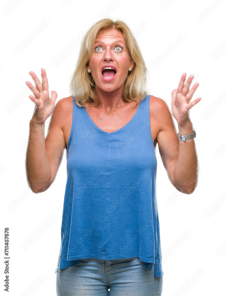 Middle age blonde woman over isolated background crazy and mad shouting and yelling with aggressive expression and arms raised. Frustration concept. Middle age blonde woman over isolated background crazy and mad shouting and yelling with aggressive expression and arms raised. Frustration concept.