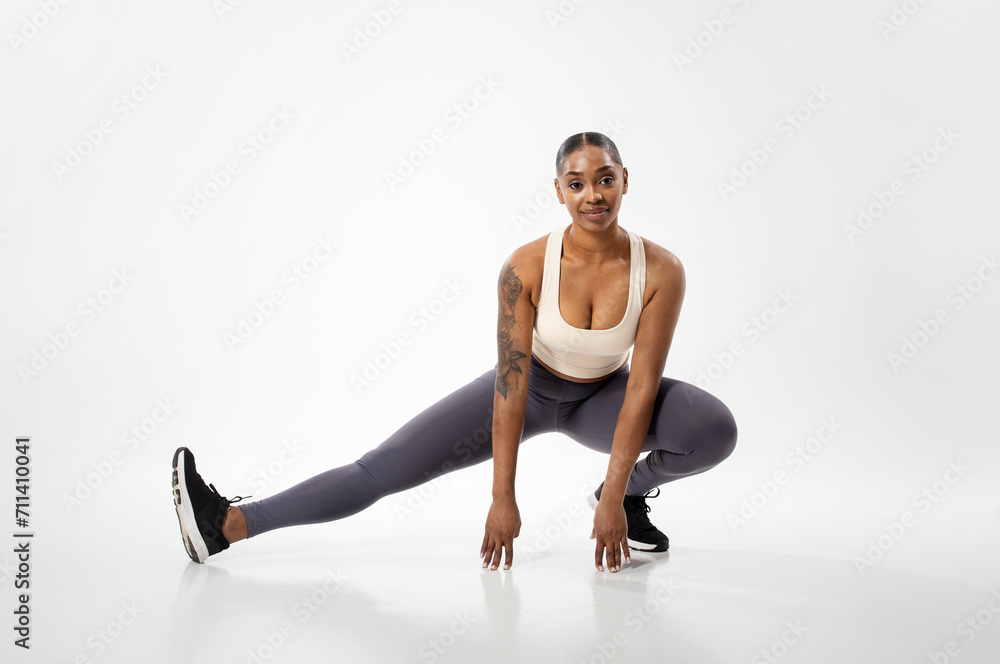 Athletic african american woman exercising stretching legs muscles, white background Athletic african american woman exercising stretching legs muscles, white background