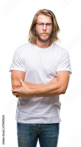 Young handsome man with long hair wearing glasses over isolated background skeptic and nervous, disapproving expression on face with crossed arms. Negative person.