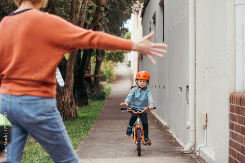 Mum reaching out to high-five son riding a bike photo