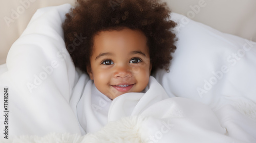 Um bebe afro com cabelo crespo enrolado na coberta branca  photo
