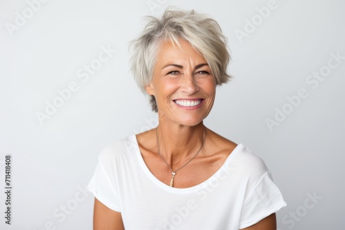 Portrait of a smiling senior woman with short hair against white background