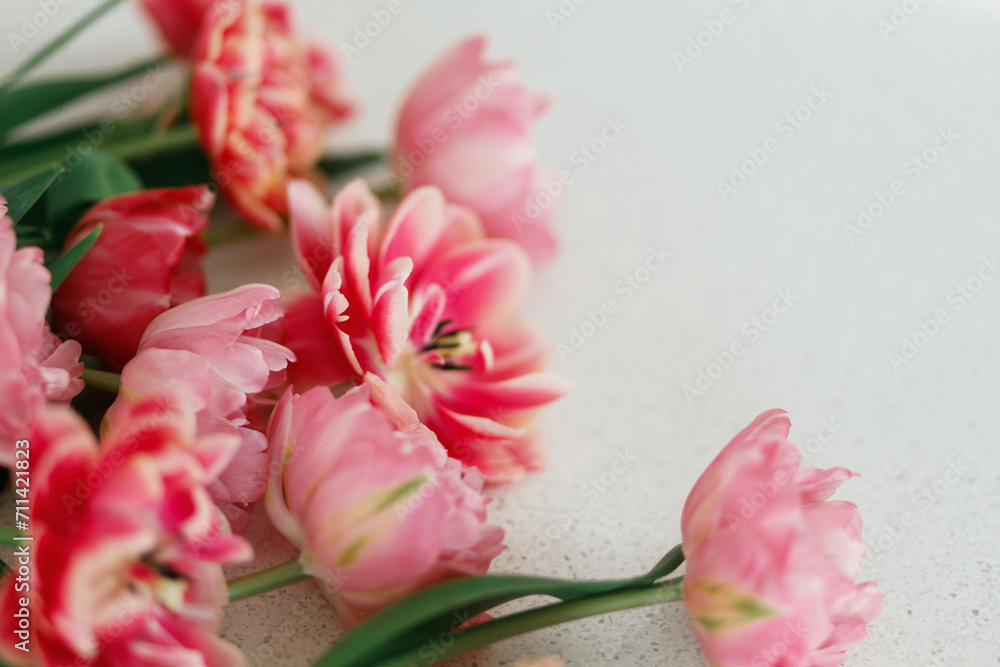 Obraz premium Beautiful tulips on grey stone background, space for text. Stylish floral bouquet. Happy Valentines day and happy mother's day. Tender pink and red flowers wallpaper