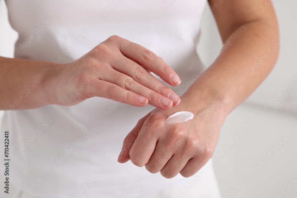 Woman applying cosmetic cream onto hand on blurred background, closeup Woman applying cosmetic cream onto hand on blurred background, closeup