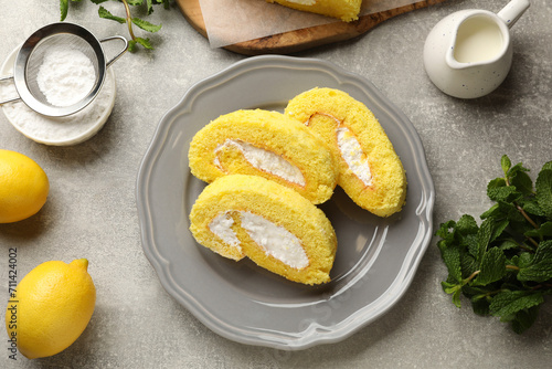 Delicious cake roll, lemons, mint and powdered sugar on grey table, flat lay