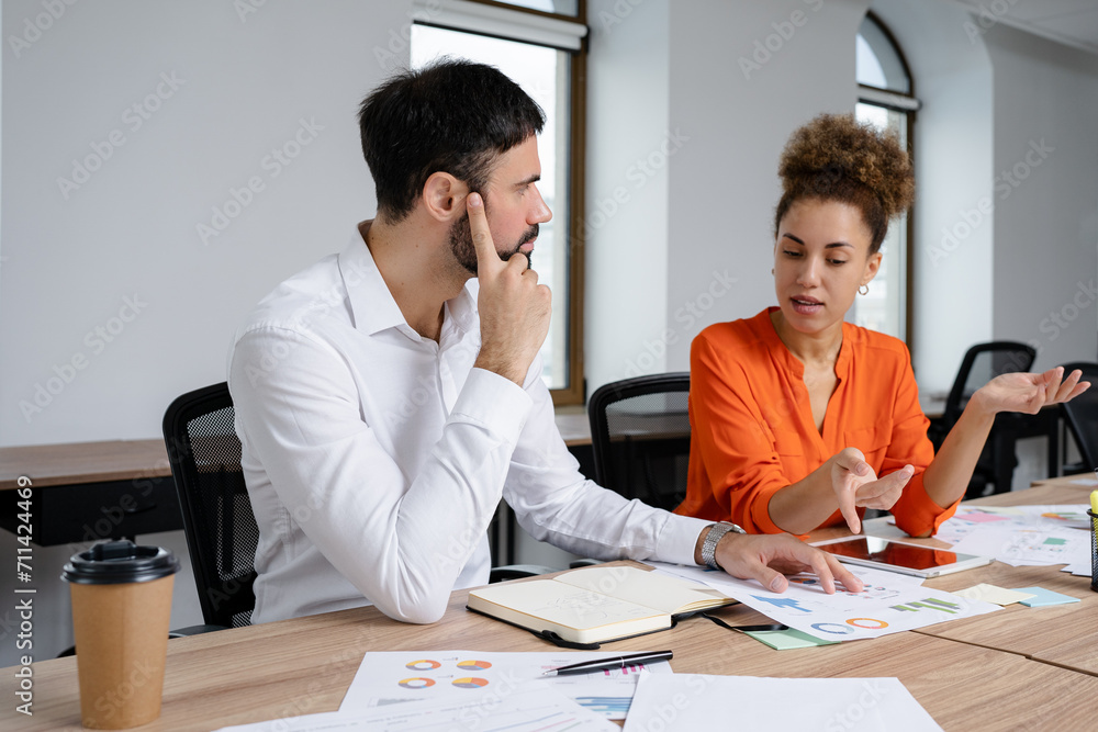Happy young entrepreneurs having a discussion while sitting together at a table. Happy young entrepreneurs having a discussion while sitting together at a table.