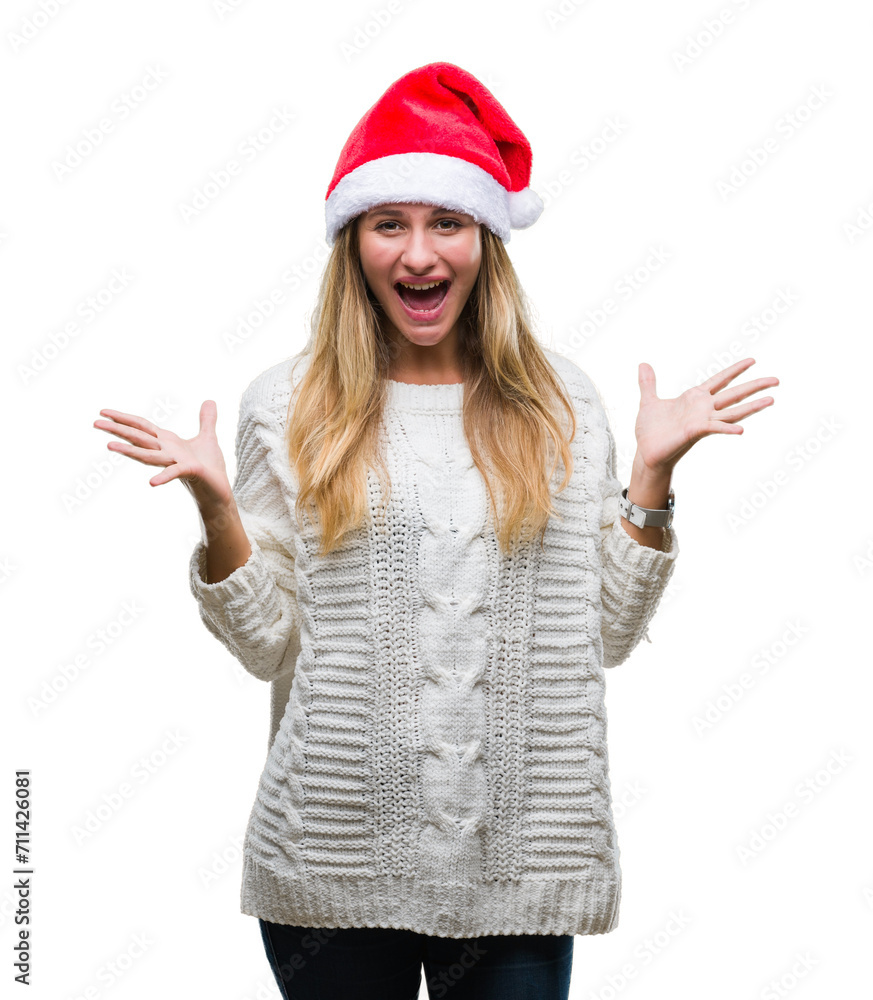 Young beautiful blonde woman wearing christmas hat over isolated background celebrating crazy and amazed for success with arms raised and open eyes screaming excited. Winner concept Young beautiful blonde woman wearing christmas hat over isolated background celebrating crazy and amazed for success with arms raised and open eyes screaming excited. Winner concept