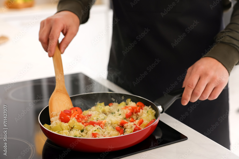 Man cooking dish on cooktop indoors, closeup Man cooking dish on cooktop indoors, closeup