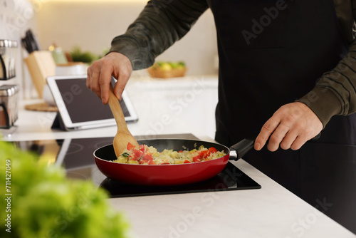 Man cooking dish on cooktop in kitchen, closeup