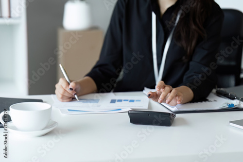 Businesswoman using a calculator to calculate numbers on a company's financial documents, she is analyzing historical financial data to plan how to grow the company. Financial concept