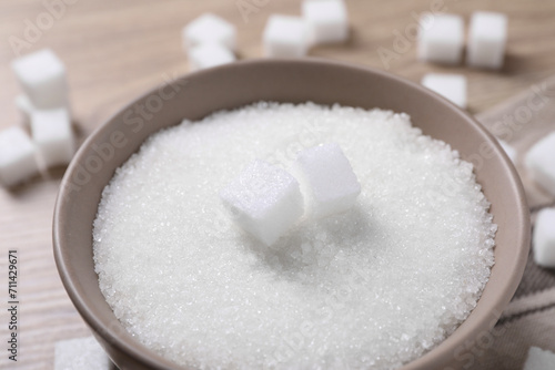 Different types of white sugar in bowl on table, closeup