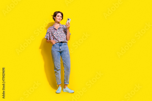 Full body portrait of lovely lady use smart phone empty space ad blank isolated on yellow color background