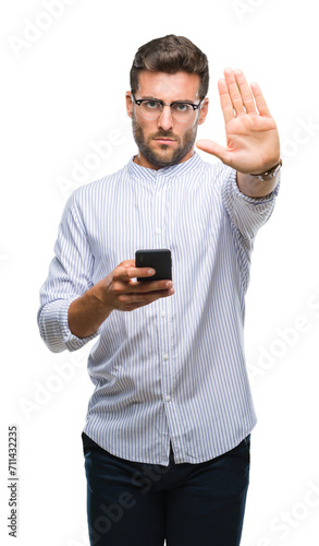 Young handsome man texting using smartphone over isolated background with open hand doing stop sign with serious and confident expression, defense gesture