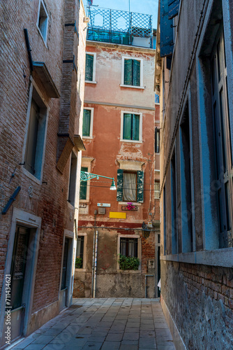 Lonely path way along the Venetian city with high facades and mystic shadows