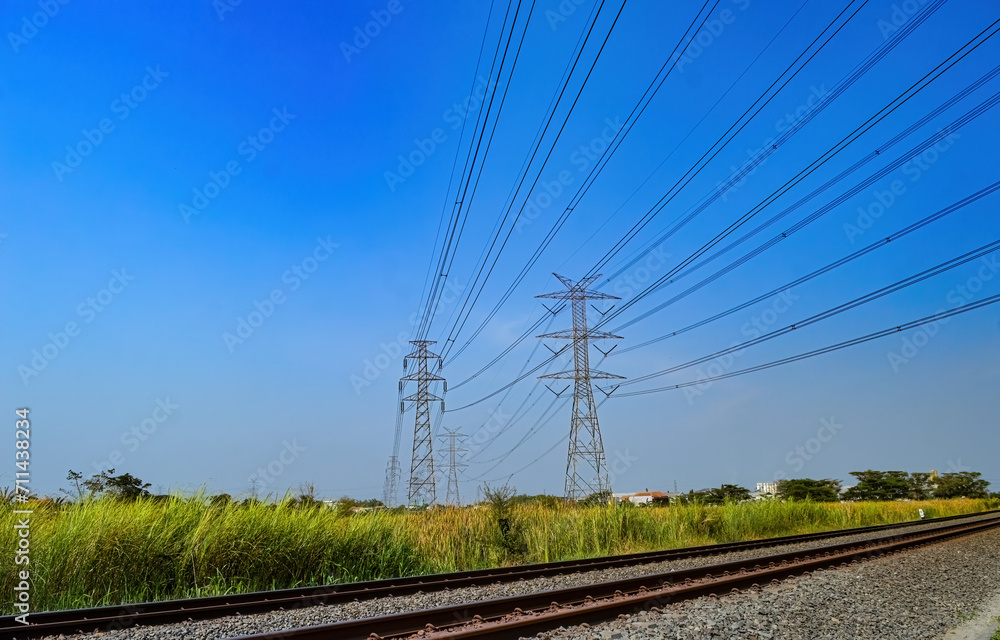two towers of high-voltage electricity poles that cross over the double-track railroad tracks