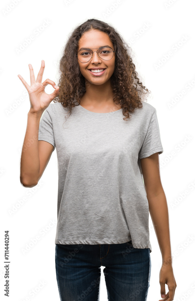 Beautiful young hispanic woman wearing glasses smiling positive doing ok sign with hand and fingers. Successful expression. Beautiful young hispanic woman wearing glasses smiling positive doing ok sign with hand and fingers. Successful expression.