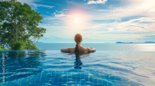 Woman swimming in infinity pool on Caribbean vacation looking at ocean scenic landscape