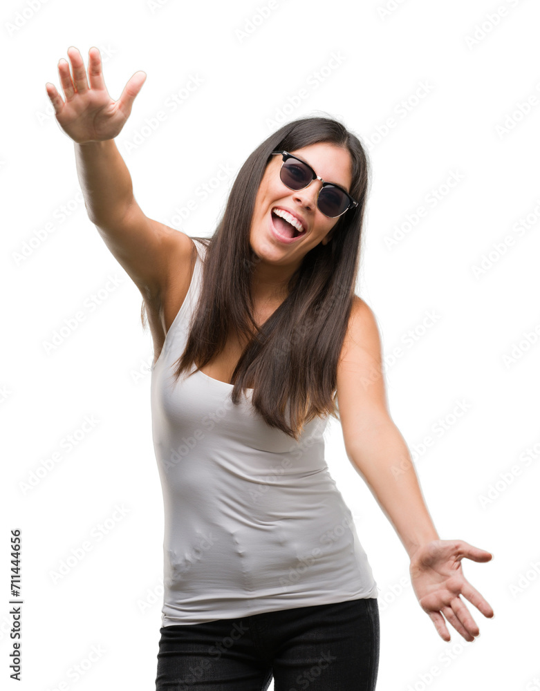 Young beautiful hispanic wearing sunglasses looking at the camera smiling with open arms for hug. Cheerful expression embracing happiness. Young beautiful hispanic wearing sunglasses looking at the camera smiling with open arms for hug. Cheerful expression embracing happiness.