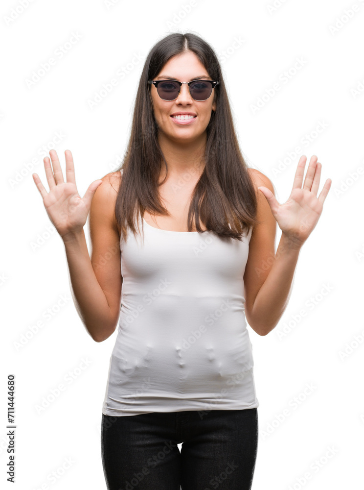 Young beautiful hispanic wearing sunglasses showing and pointing up with fingers number ten while smiling confident and happy. Young beautiful hispanic wearing sunglasses showing and pointing up with fingers number ten while smiling confident and happy.