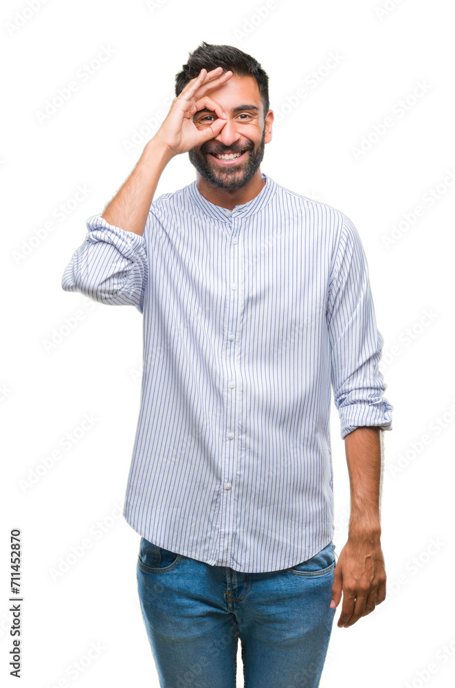 Adult hispanic man over isolated background doing ok gesture with hand smiling, eye looking through fingers with happy face. Adult hispanic man over isolated background doing ok gesture with hand smiling, eye looking through fingers with happy face.
