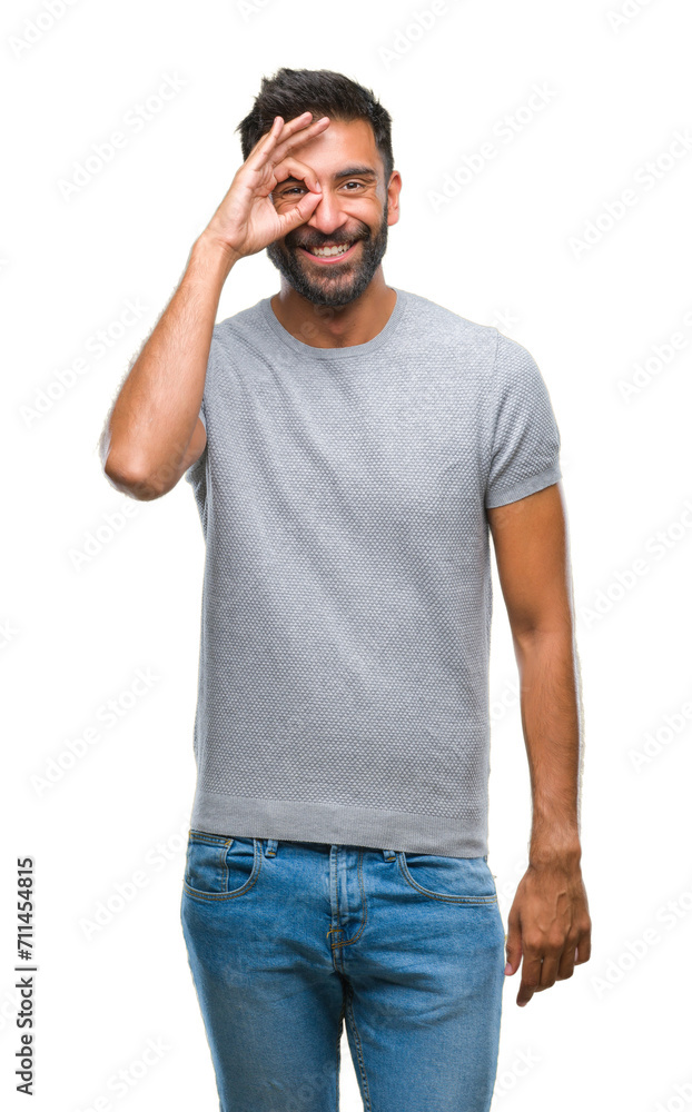 Adult hispanic man over isolated background doing ok gesture with hand smiling, eye looking through fingers with happy face. Adult hispanic man over isolated background doing ok gesture with hand smiling, eye looking through fingers with happy face.
