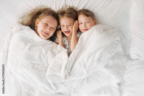 Happy family - portrait of children and mother in bed. Happy, love and fun at home. Family, childhood.