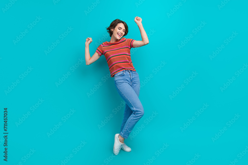Full length photo of cheerful adorable girl with raised hands celebrate holiday isolated on cyan color background Full length photo of cheerful adorable girl with raised hands celebrate holiday isolated on cyan color background