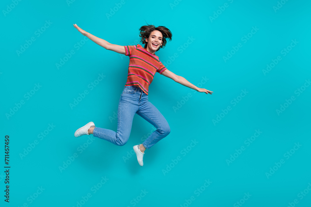 Photo of glad positive girl wearing stylish outfit flying air with open hands isolated on cyan color background
