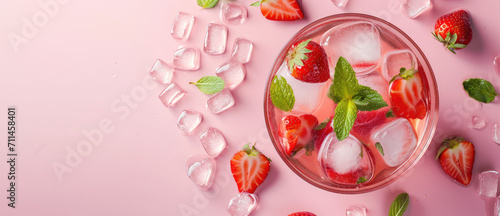 Strawberry Sangria Cocktail, copy space. Refreshing glass of strawberry sangria with ice cubes, perfect for summer days on pink background.