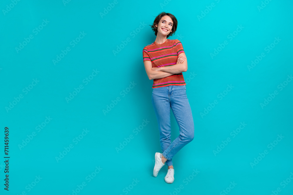 Full length photo of lovely adorable girl with crossed arms wear trendy clothes looking empty space isolated on cyan color background Full length photo of lovely adorable girl with crossed arms wear trendy clothes looking empty space isolated on cyan color background