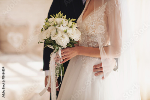 Bride holding a beautiful white wedding bouquet. Sensual wedding couple.Romantic moments of newlyweds. Wedding photo. Wedding flowers bouquet held by a bride during her special day.