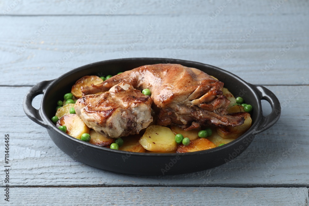 Tasty cooked rabbit with vegetables in baking dish on grey wooden table Tasty cooked rabbit with vegetables in baking dish on grey wooden table