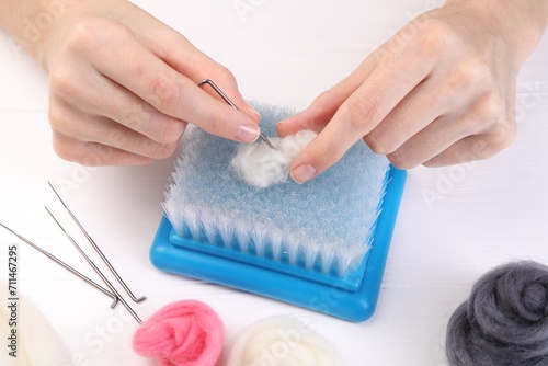 Woman felting from wool at white wooden table, closeup