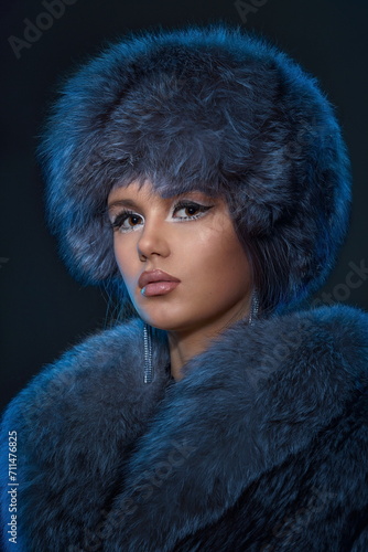 Fotografija Portrait of a young girl with exquisite makeup wearing a blue fur coat and hat