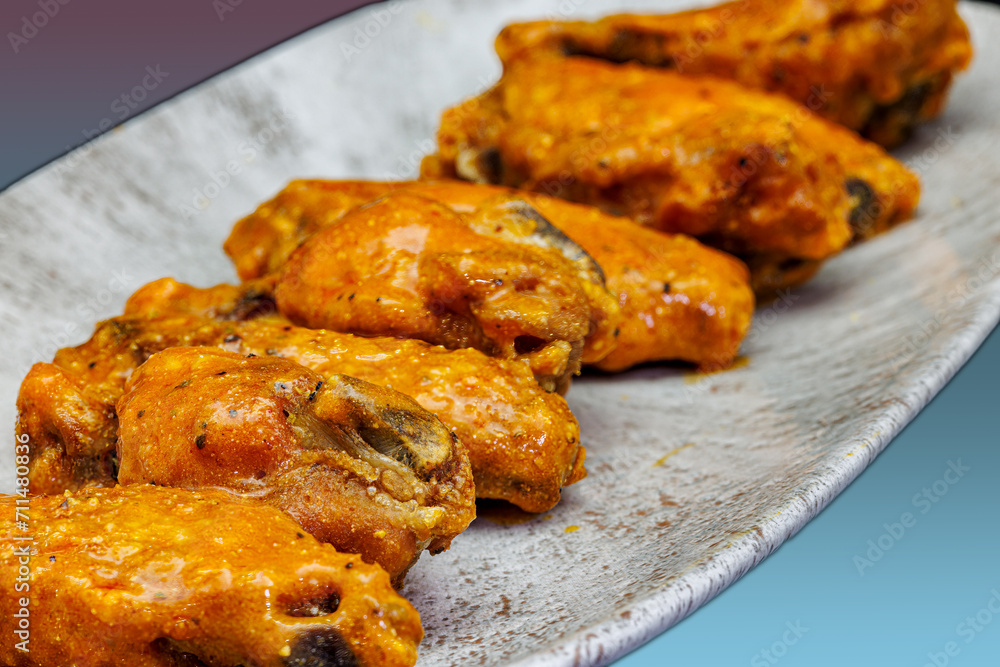 Plate of Buffalo chicken wings on a magenta and light blue background Plate of Buffalo chicken wings on a magenta and light blue background