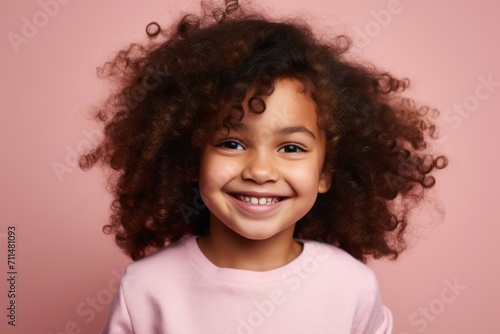 Portrait of a cute little african american girl with curly hair on pink background © Loli