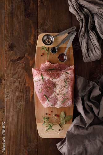 a piece of fresh raw pork meat with spices on a brown wooden table. Meat with spices