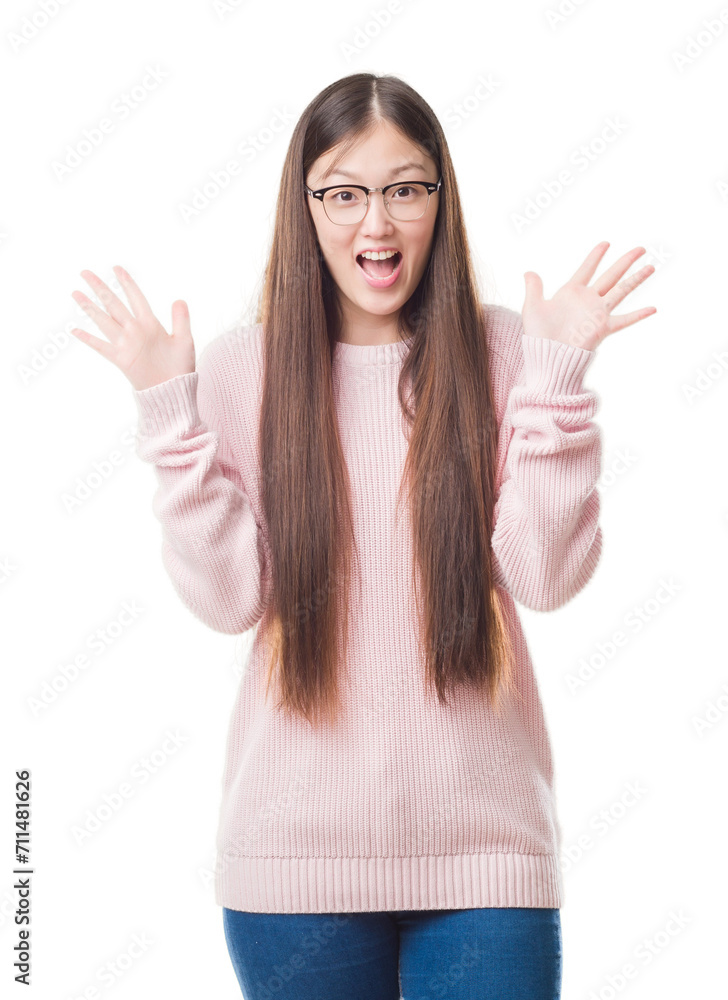 Young Chinese woman over isolated background wearing glasses celebrating crazy and amazed for success with arms raised and open eyes screaming excited. Winner concept Young Chinese woman over isolated background wearing glasses celebrating crazy and amazed for success with arms raised and open eyes screaming excited. Winner concept