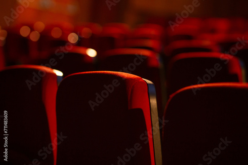 Detalhe de um teatro vazio. Várias fileiras de poltronas vermelhas fotografadas por trás. Fotografia com foco restrito. photo