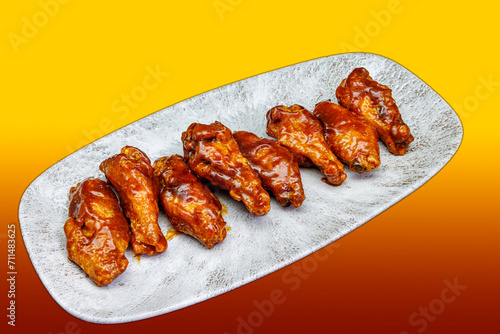 Plate of barbecued chicken wings on a yellow and red gradient background