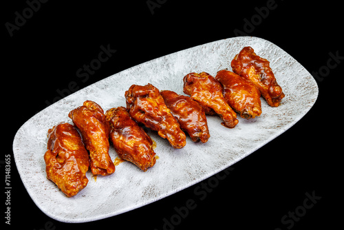 Plate of barbecue chicken wings on black background