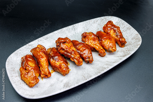 Plate of barbecue chicken wings on black background