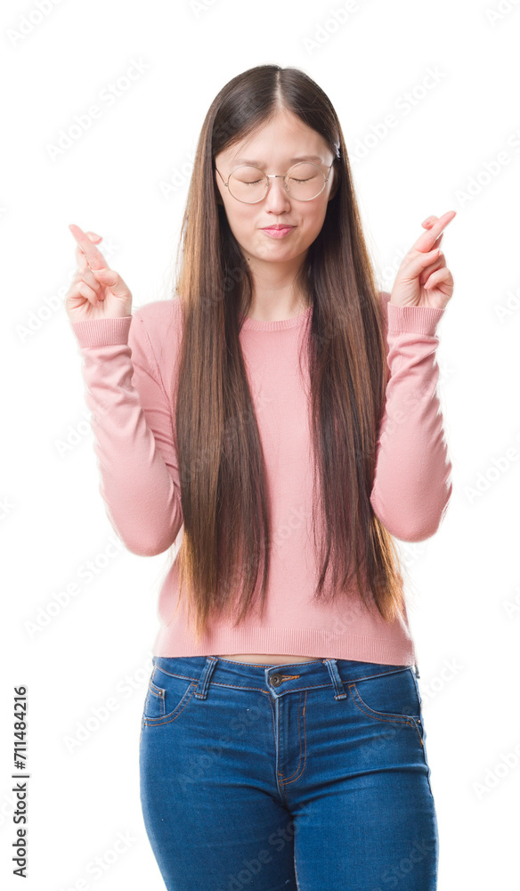 Young Chinese woman over isolated background wearing glasses smiling crossing fingers with hope and eyes closed. Luck and superstitious concept. Young Chinese woman over isolated background wearing glasses smiling crossing fingers with hope and eyes closed. Luck and superstitious concept.