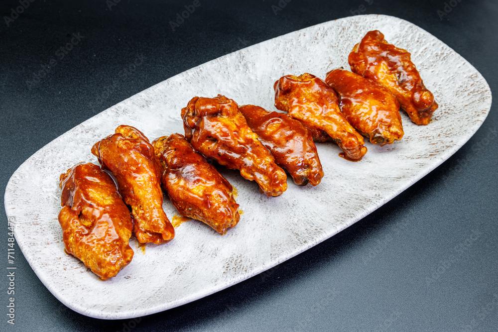 Plate of barbecue chicken wings on black background Plate of barbecue chicken wings on black background