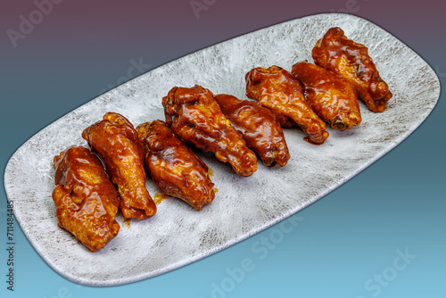 Plate of barbecued chicken wings on a magenta and light blue gradient background