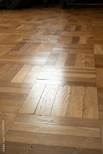 Wood tile or parquet flooring inside apartment room. Close up shot, reflected natural window light, shallow depth of field, no people