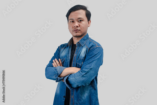 Young Asian Man folded arms looking at camera with bad face expression on isolated background