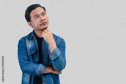 Young Asian Man thinking about question, pensive expression. while hand on chin. On isolated background.